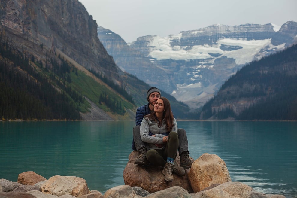 Couple sitting on a rock at Lake Louise during their photoshoot