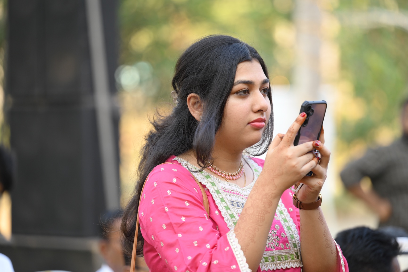 beautiful girl in pink outfit capturing an intimate wedding moment on her phone