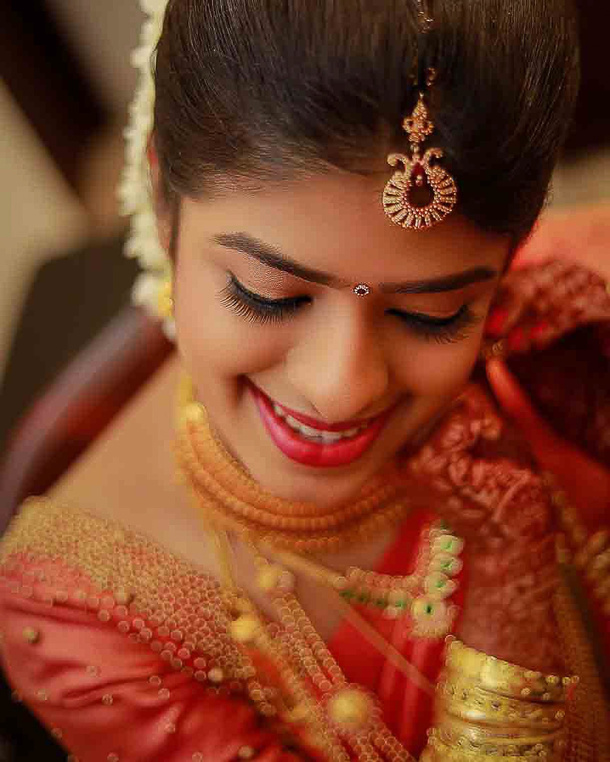 Palakkad bride close up shot she is in a red saree and full of ornaments, the photograph is taken during her Palakkad wedding photography session very artistically