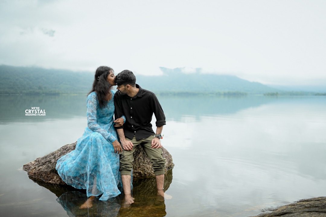 Artistic save the date photograph with a groom lifting the bride against a traditional Kerala backdrop.