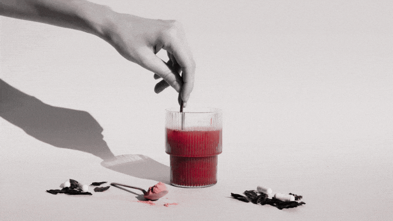 a person's hand mixing a healthy drink