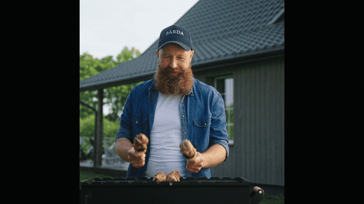 a man with a beard and a beard, standing in front of a grill