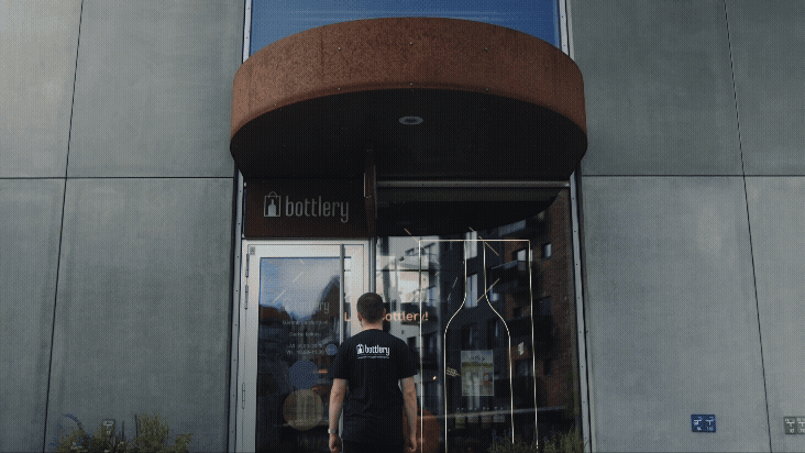 a man in a black shirt is standing in front of a building, wine store