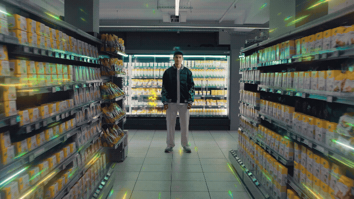 a man standing in a store with a lot of shelves holding his phone