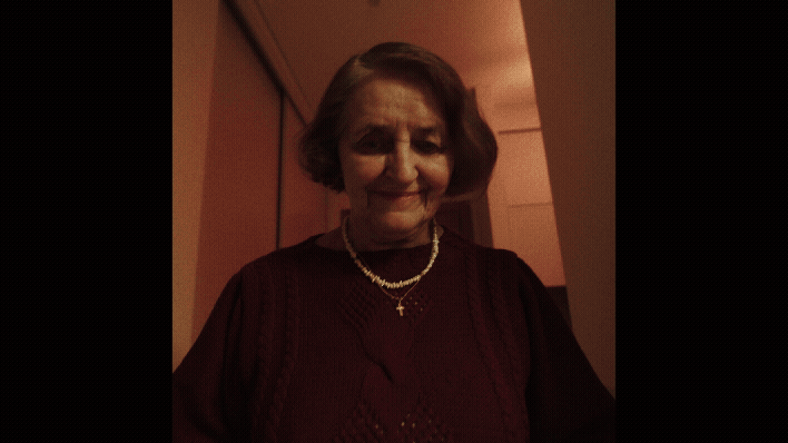 a woman in a red dress and pearls necklaces going to her grandson with white hoodie